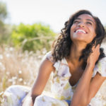 woman in dress smiling in field of flowers