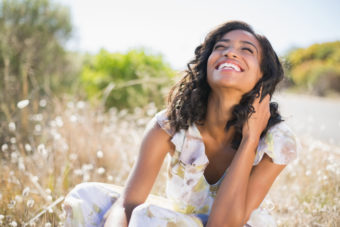 woman in dress smiling in field of flowers