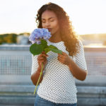 woman smelling scent of a blue flower